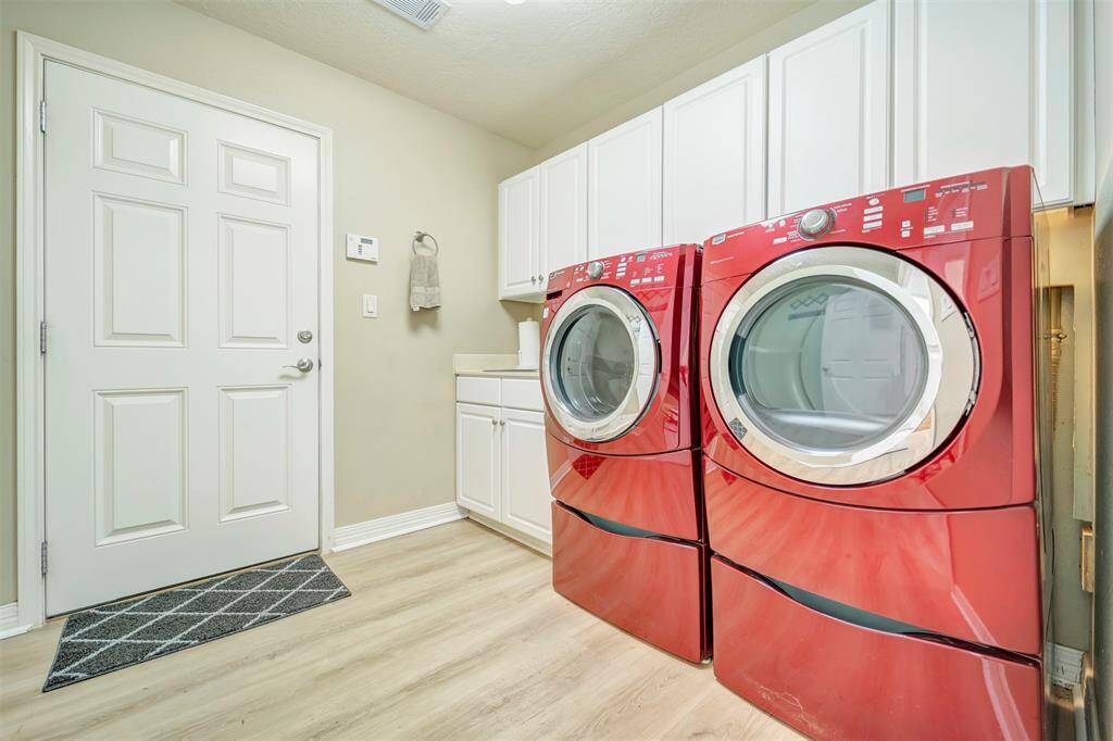 Spacious laundry room with tons of storage and sink leads to garage entry.