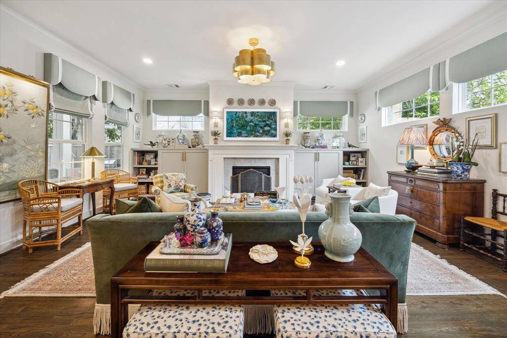 Enhanced with a custom fireplace surround, attractive built-ins with unlacquered brass hardware, transom windows, elegant custom window treatments and designer Visual Comfort sconces and light fixture - this space is a real showstopper!  Beauty by design!