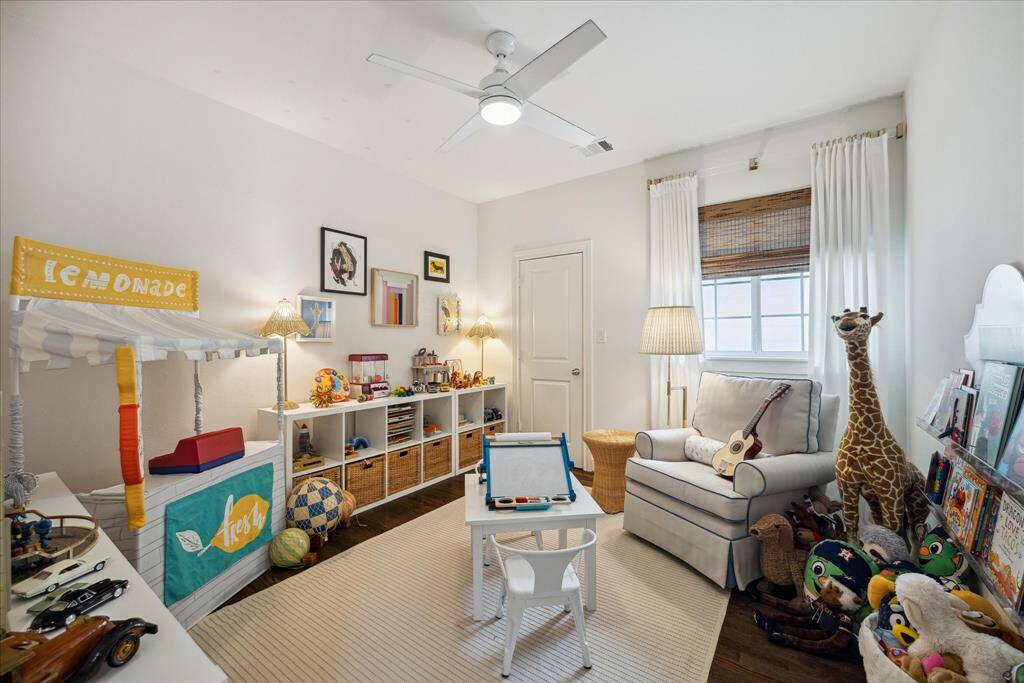 This bedroom is currently being used as a playroom. The room's beauty is enriched by the custom acrylic curtain rod and hooks curtains that are complemented by natural bamboo shades.