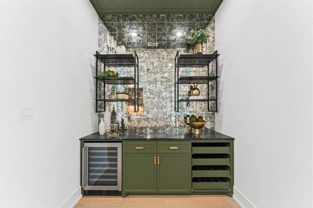 Stunning wine room offers smoky mirror backsplash and open iron shelves.