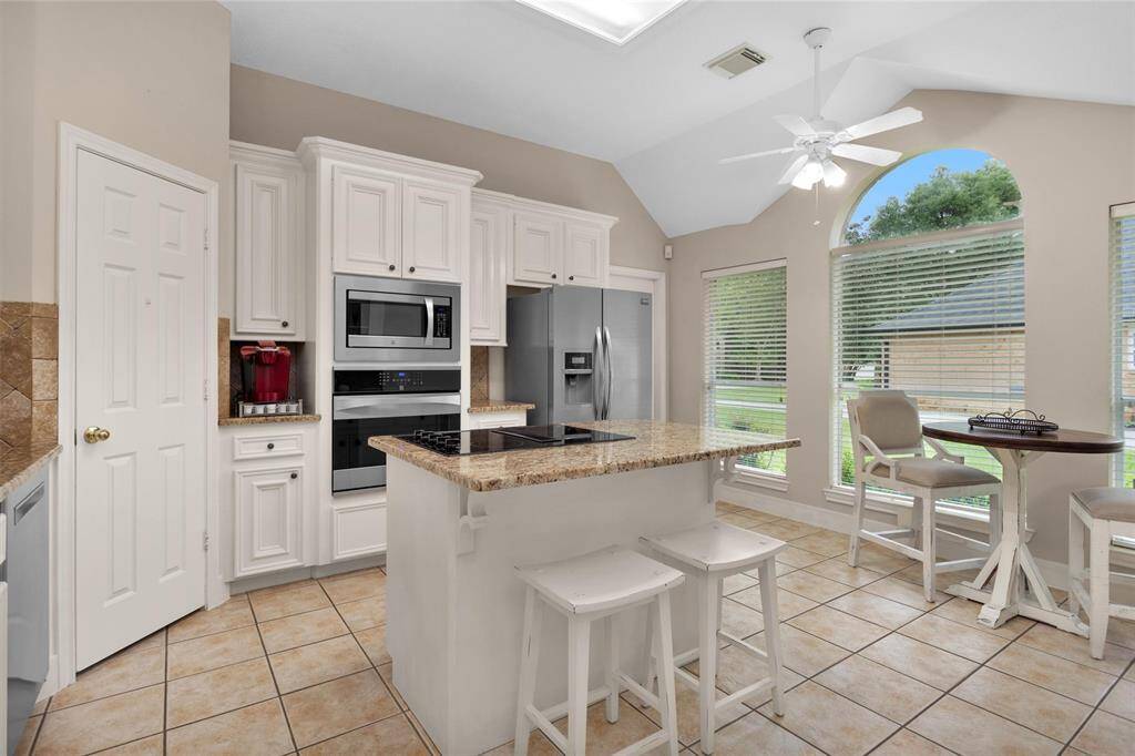 Elevate your cooking experience in this kitchen featuring a high ceiling, sleek granite countertops, and a stylish updated backsplash.