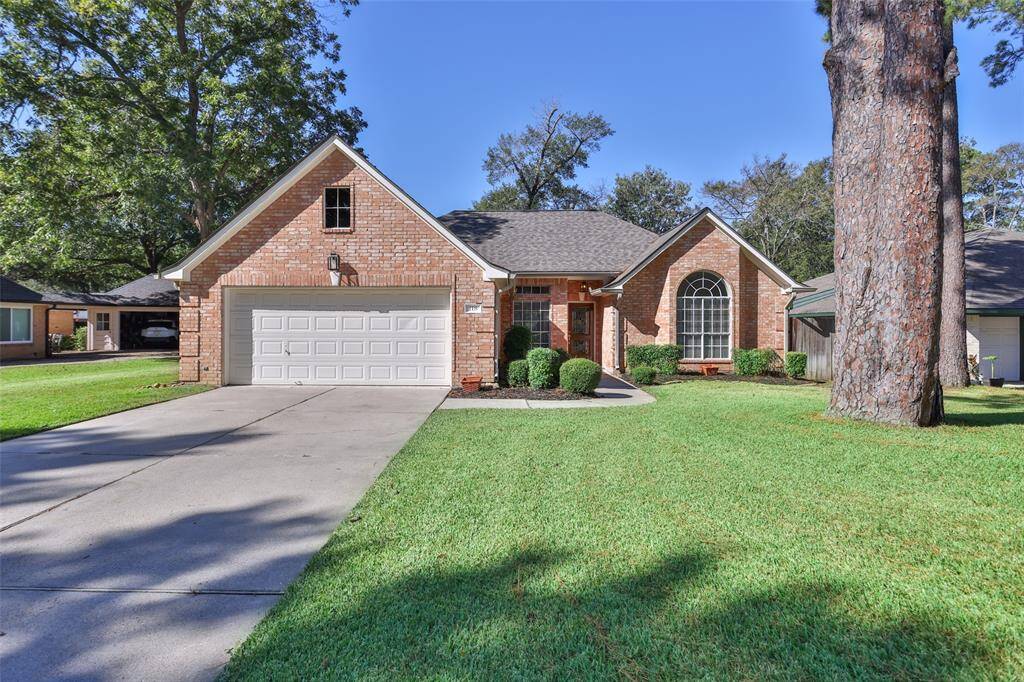 Charming single-story brick home with an attached two-car garage, nestled in a serene neighborhood with mature trees.