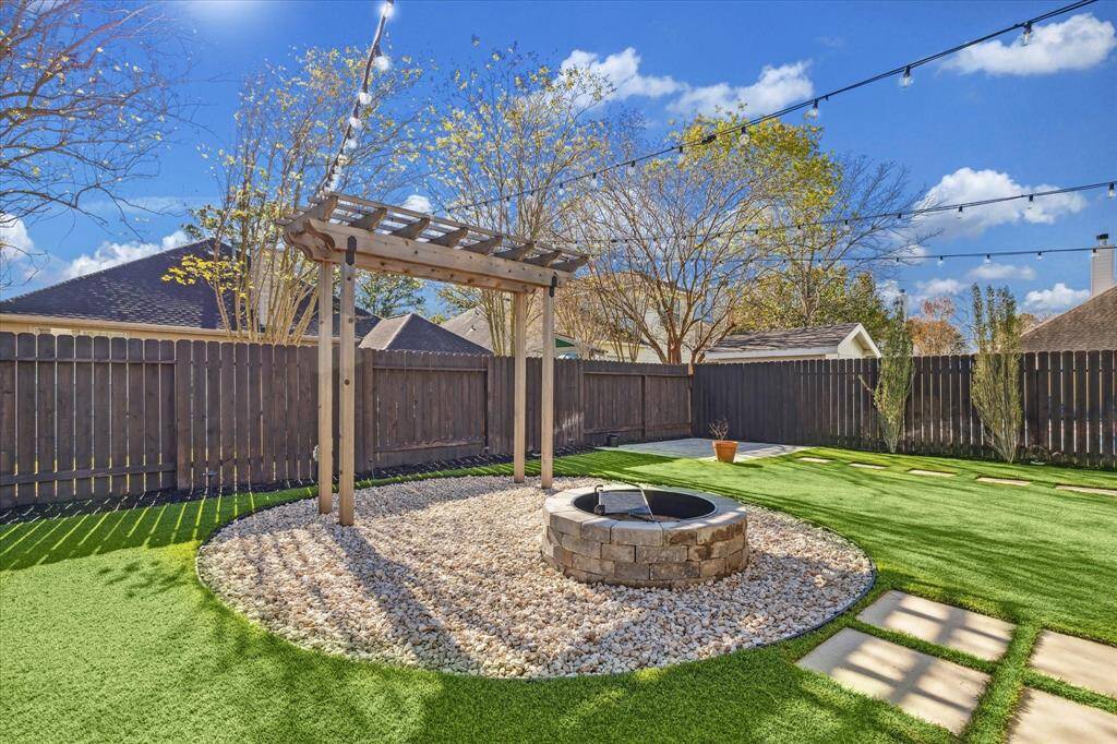 Backyard complete with luxury turf, new landscaping, a custom built arbor, and a wood burning fire pit with a fitted grill grate for the outdoor cooking enthusiast!