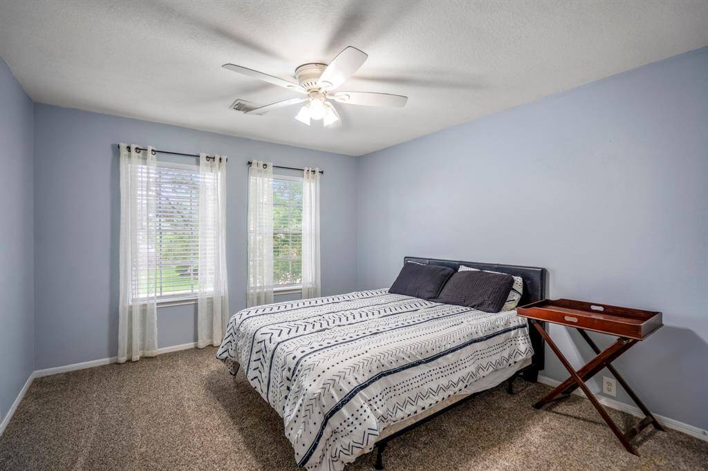 Tranquil secondary bedroom, featuring natural lighting from large windows.