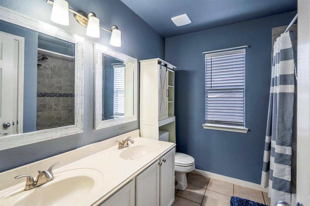 Step into this stylish bathroom, complete with double sinks and modern fixtures.