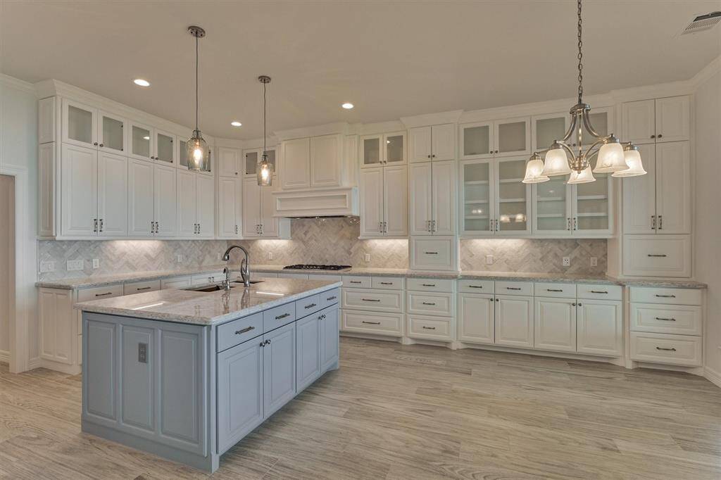 The cabinetry seamlessly extends into a serving-style buffet adjacent to the dining area, providing both convenience and elegance. This well-designed kitchen includes soft-close drawers and cabinets, two appliance garages to keep everyday items neatly tucked away, seeded glass cabinet doors, under-cabinet lighting, and solid wood panel cabinetry throughout the home—highlighting both quality craftsmanship and thoughtful design.