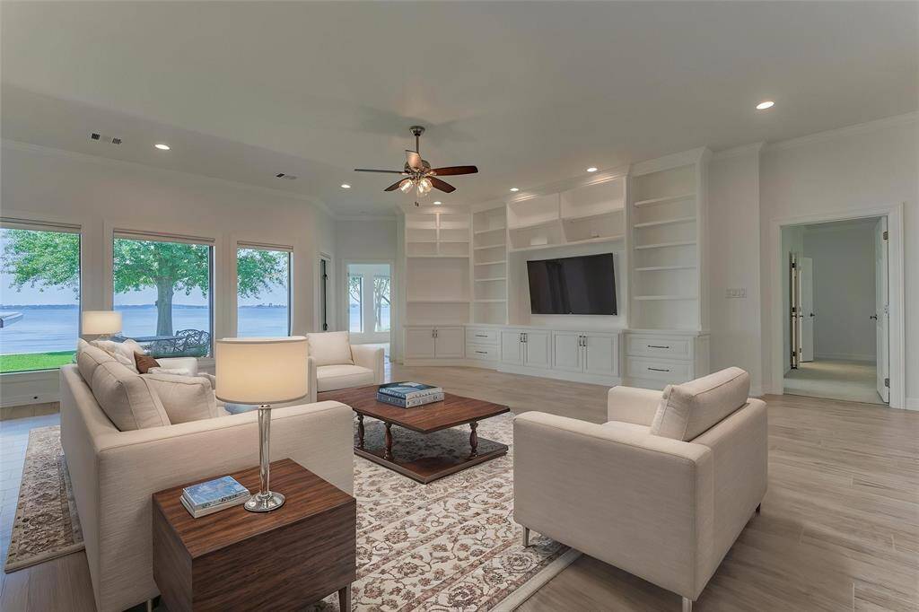 Looking back from the kitchen, you’re treated to stunning lake views and a glimpse of two thoughtfully designed primary suite areas, each offering comfort, privacy, and a seamless connection to the home’s surroundings. Photo is virtually staged to show furniture placement.