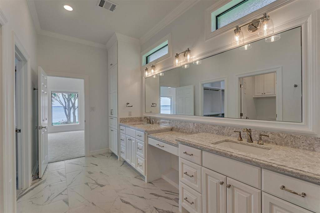 Another view of the primary bath reveals the first primary bedroom just beyond. Elevated horizontal windows allow natural light to gently filter in while maintaining a sense of privacy, adding to the room’s serene and spa-like atmosphere.