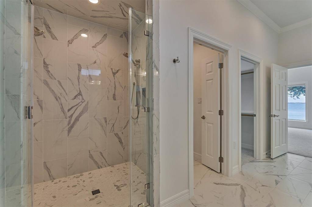 The oversized shower, measuring 48" x 60", features a seamless glass surround and an adjustable showerhead, making it ideal for ADA accessibility. Thoughtfully designed with future needs in mind, the shower and adjacent toilet area include reinforced blocking behind the sheetrock at 36" above the floor, ready for grab bar installation if desired.