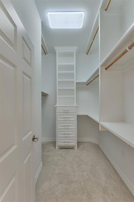 One of the two primary closets features built-in shelving and drawers and abundant hanging space, offering both organization and functionality.