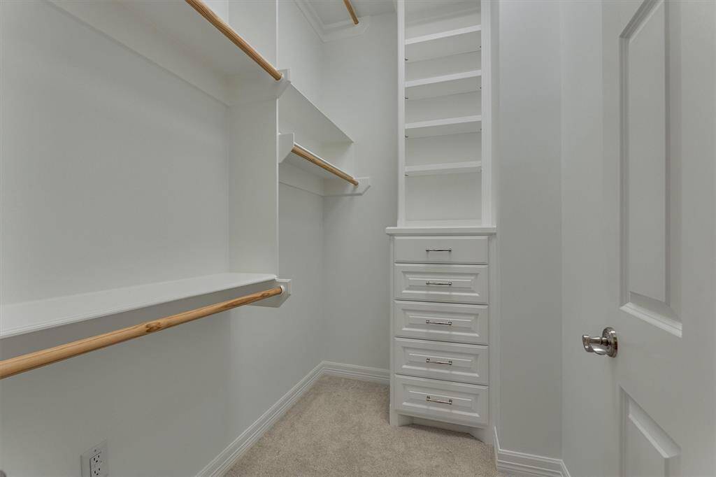 The second primary bedroom closet is also thoughtfully designed with built-in shelving and drawers, along with ample hanging space to accommodate a variety of storage needs.