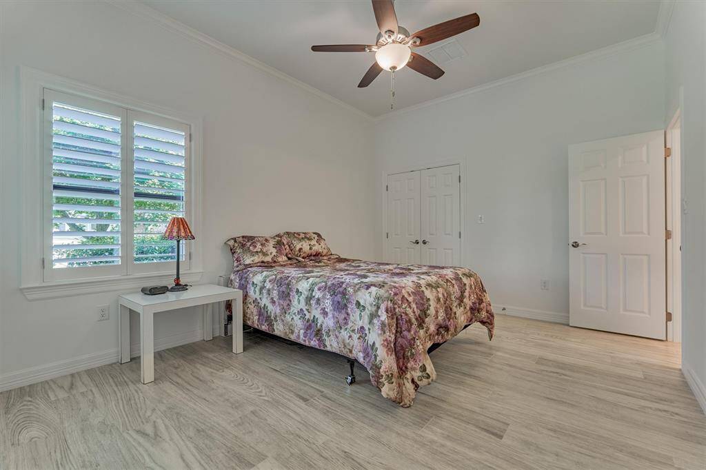 A third bedroom on the first floor offers a comfortable retreat for guests, featuring a full en-suite bath, a double-door closet, and custom wood shutters that provide both privacy and adjustable light control.