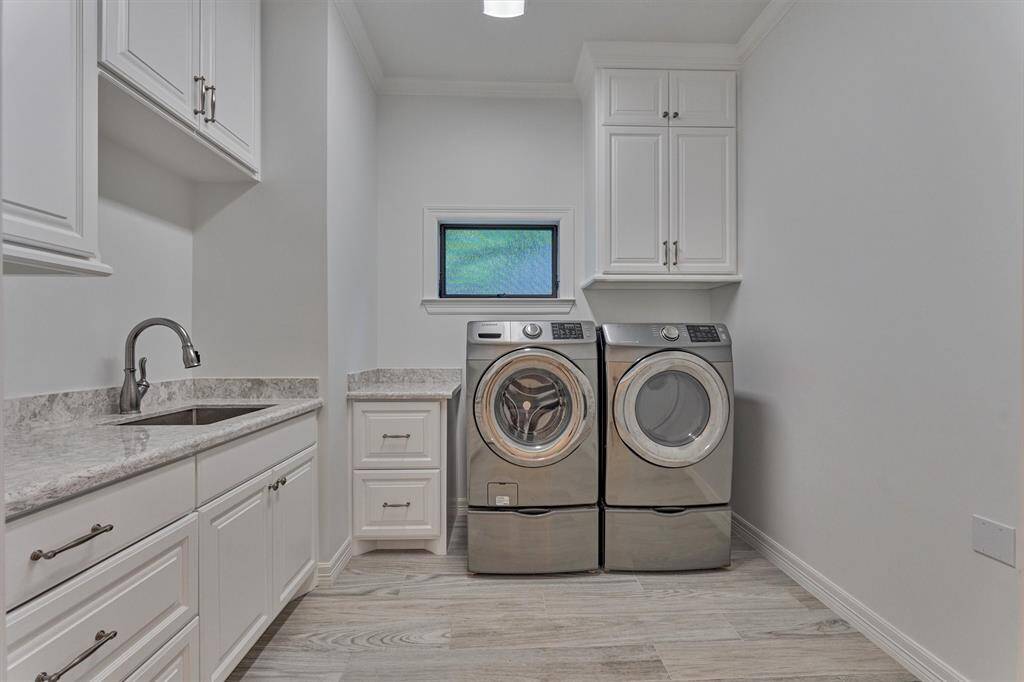 The laundry room is both sleek and stylish, offering ample storage with upper cabinets and drawers, plus plumbing in place for a future refrigerator, making it as functional as it is polished.