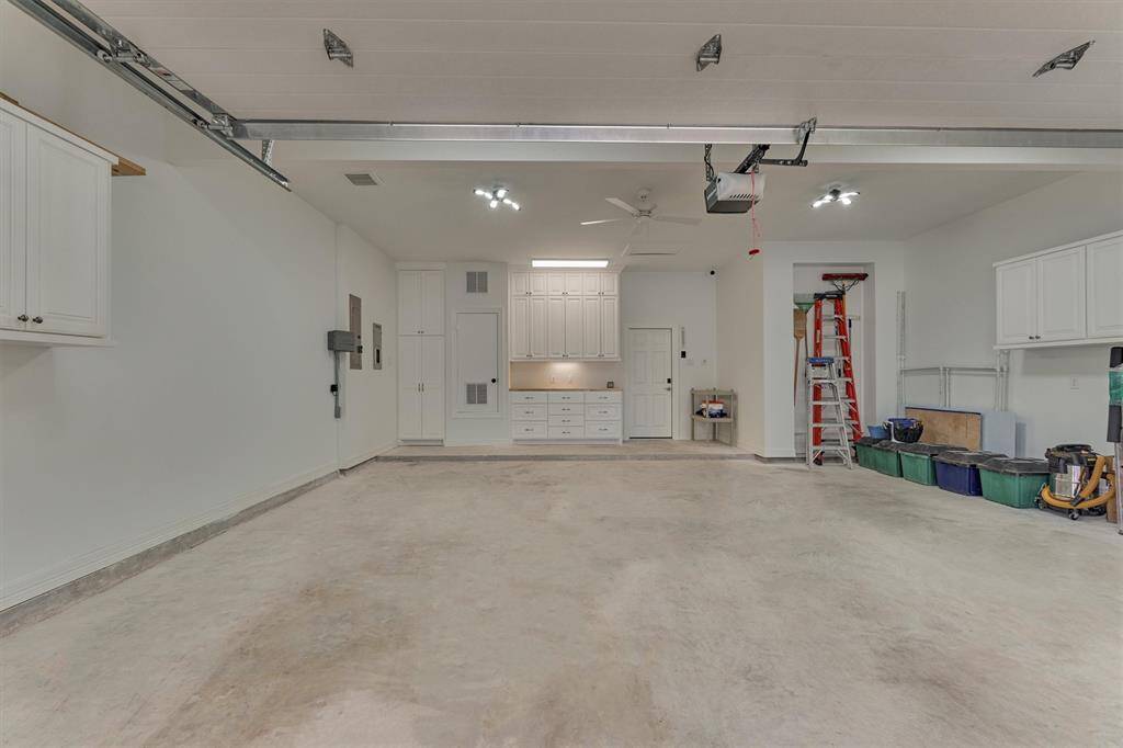 The oversized garage is equipped with built-in cabinets along three walls, offering abundant closed storage, as well as a dedicated work space with additional cabinetry. Notable features include an insulated garage door, a WiFi-enabled LiftMaster opener, and 5/8" sheetrock walls insulated with Rockwool for sound and fire resistance. A solid garage door between the garage and the main living space for added safety.