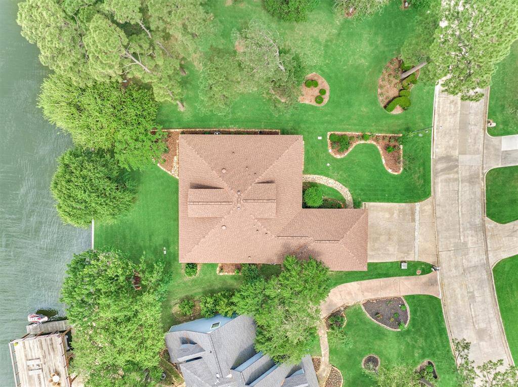 This bird’s-eye view showcases the property’s beautifully maintained landscaping, accented with stone edging throughout. The grounds feature four crepe myrtles, three Texas rose bushes, one Meyer lemon tree, and three vibrant blood orange trees, creating a lush and colorful outdoor setting.