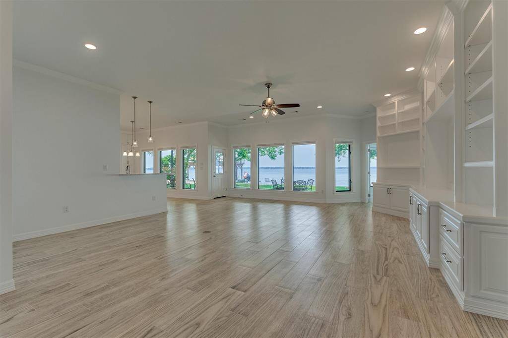 As you step inside, you're immediately welcomed by breathtaking panoramic views of Lake Conroe. The expansive living area has been fully remodeled, featuring wood-look tile flooring, custom built-ins, and wiring for surround sound, perfect for both relaxing and entertaining.