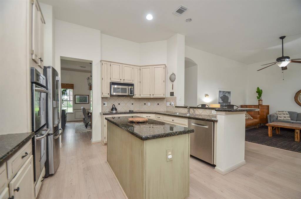 This is a bright, spacious kitchen with modern appliances, ample cabinet space, and an island, flowing seamlessly into an open-plan living area.