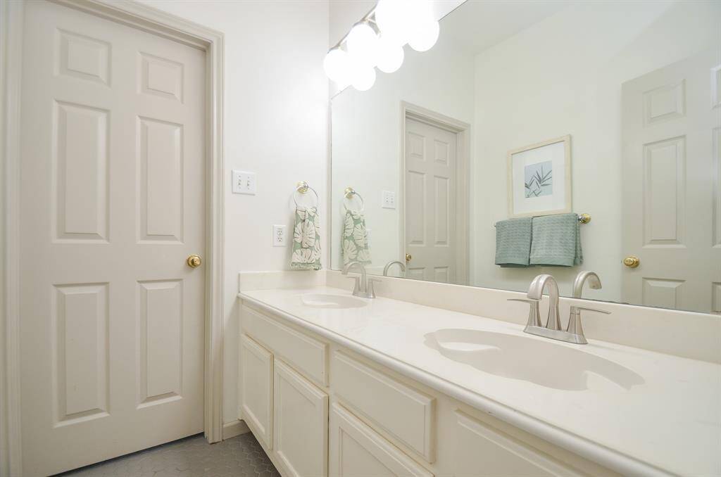 This is a clean, well-maintained bathroom featuring a dual-sink vanity with ample storage, modern fixtures, and a large mirror. It has a neutral color palette and is ready for personalization.