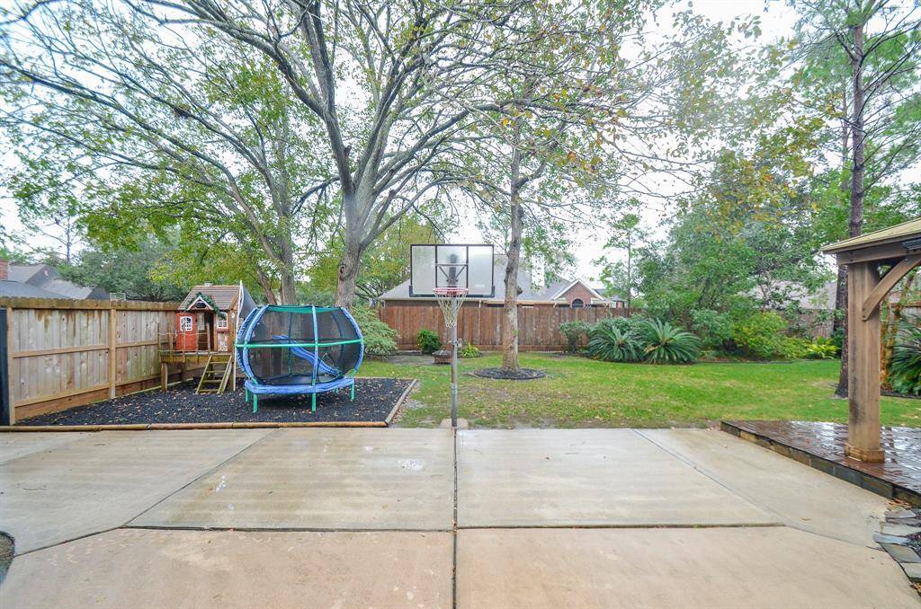 Spacious backyard with mature trees, a play area and ample lawn space, ideal for family activities and outdoor entertainment.