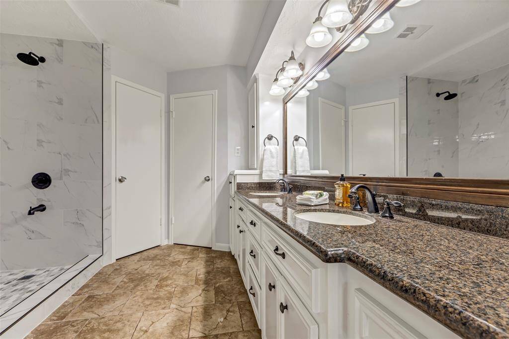 New remodeled primary bathroom with double sinks, two closets and granite countertops