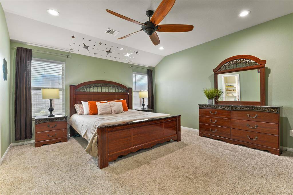 Escape to the privacy of this secluded master suite with a gambrel ceiling, recessed lighting, a ceiling fan, a pair of rear-facing windows dressed with 2-inch blinds, plush carpet, and a large walk-in closet.