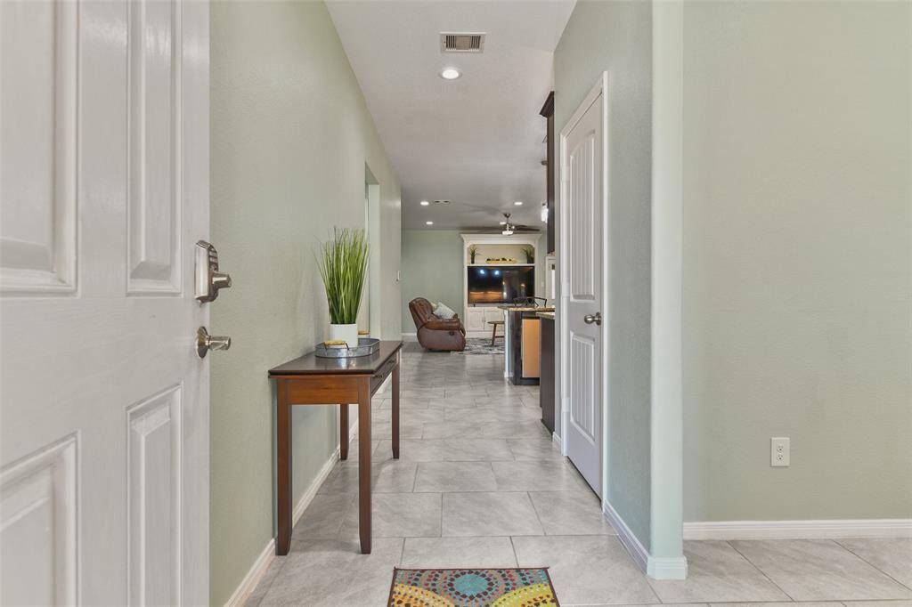 A 6-panel solid wood front door with a keyless electronic lock opens into this light, bright, and inviting floorplan with attractive stone-look tile flooring, a soft sage paint selection, and recessed lighting extending throughout the foyer, dining room, and family room.