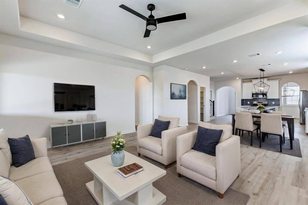 This spacious great room seamlessly flows into the open kitchen, offering a perfect layout for entertaining. Tall ceilings, recessed lighting, and archways add character, while neutral walls and stylish flooring create a modern yet inviting ambiance. **This is a picture of a Rylan Floor Plan from another Saratoga Homes.**