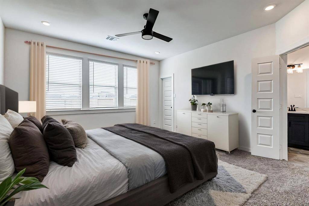 The luxurious primary suite features plush carpeting, large windows, and recessed lighting for a cozy yet airy feel. A ceiling fan adds comfort, and the ensuite bath provides a spa-like retreat. This serene space is a perfect escape after a long day! **This is a picture of a Rylan Floor Plan from another Saratoga Homes.**