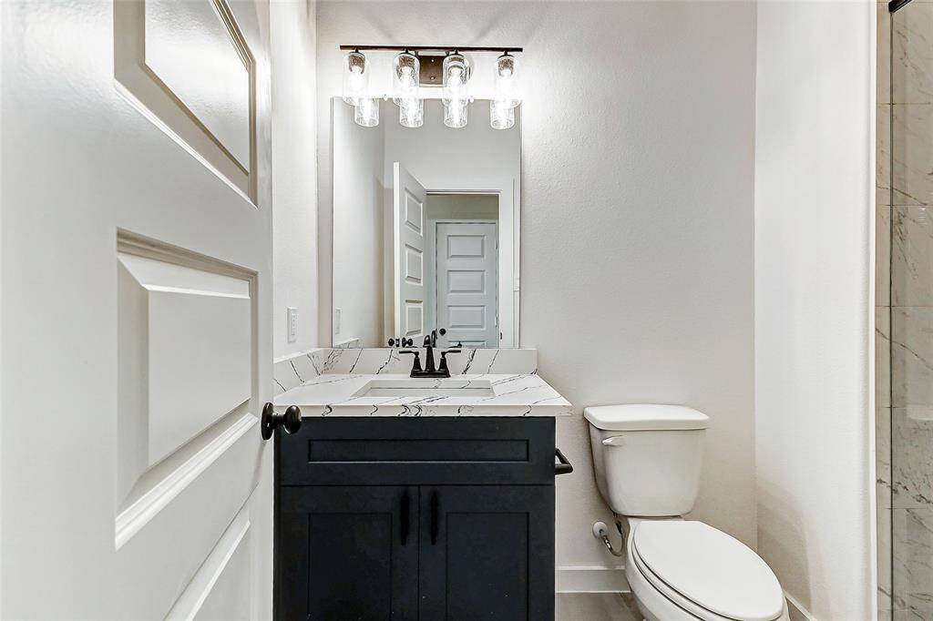 This stylish bathroom features a modern vanity with quartz countertops, elegant lighting, and a sophisticated black and white color scheme. This is a picture of a Rylan Floor Plan from another Saratoga Homes.