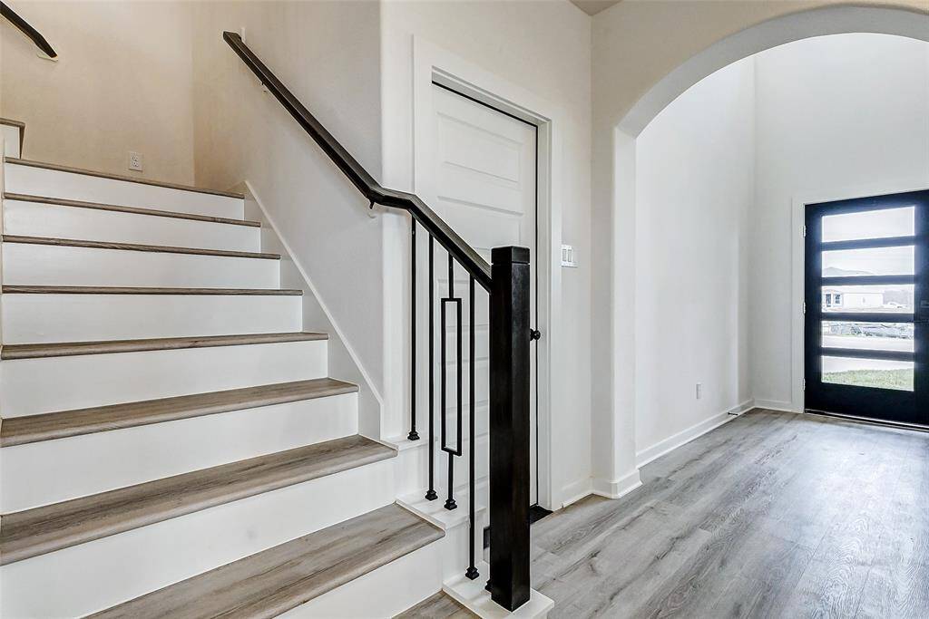Step into elegance! This grand entryway features soaring ceilings, modern iron railings, and a sleek black door that makes a bold first impression. **This is a picture of a Rylan Floor Plan from another Saratoga Homes.**