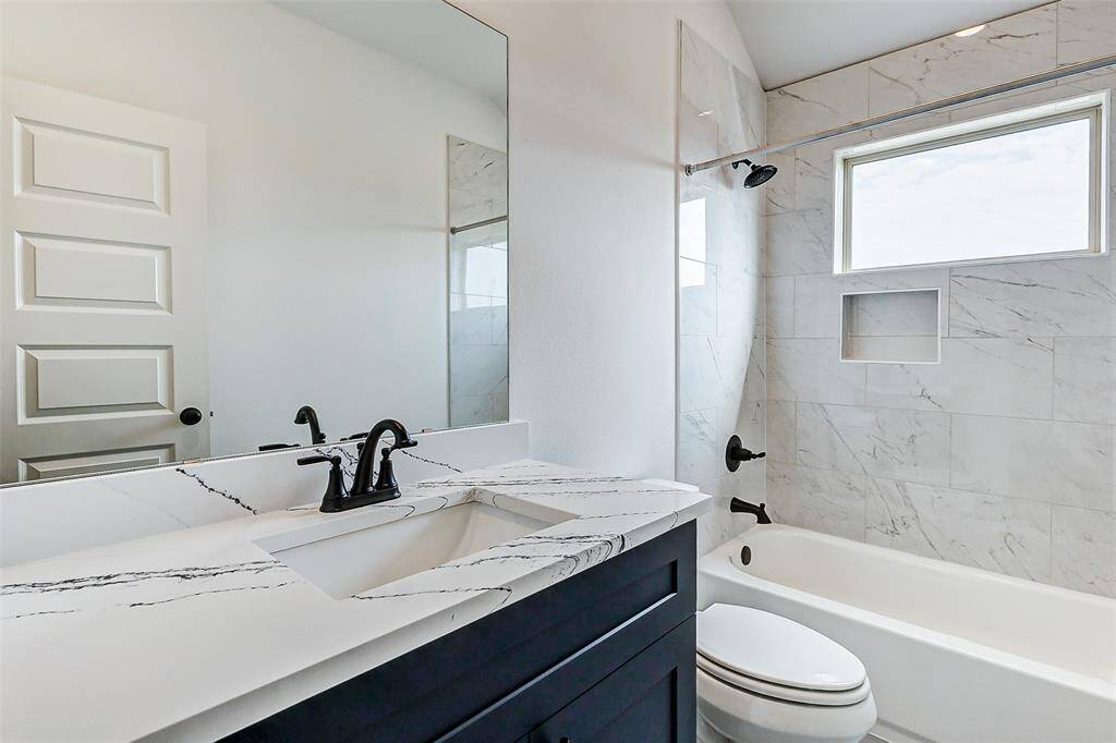 A luxurious secondary bath featuring a deep soaking tub, marble-inspired tile, and sleek matte black fixtures. The perfect blend of sophistication and functionality! **This is a picture of a Rylan Floor Plan from another Saratoga Homes.**