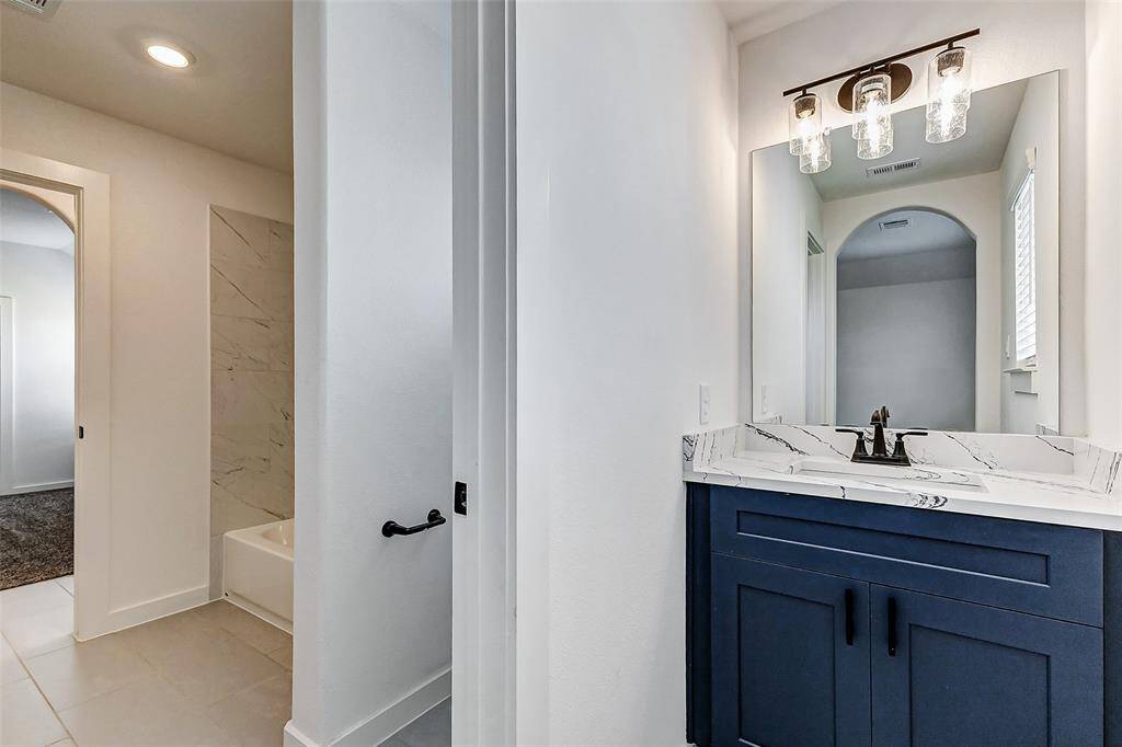 A stylish and convenient half-bath featuring a modern navy vanity, elegant marble countertops, and designer lighting for a refined look. **This is a picture of a Rylan Floor Plan from another Saratoga Homes.**