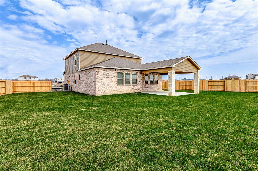 A charming blend of brick and siding enhances this home's exterior, while large windows invite natural light inside. The covered patio and expansive lawn make this home’s backyard a standout feature. **This is a picture of a Rylan Floor Plan from another Saratoga Homes.**