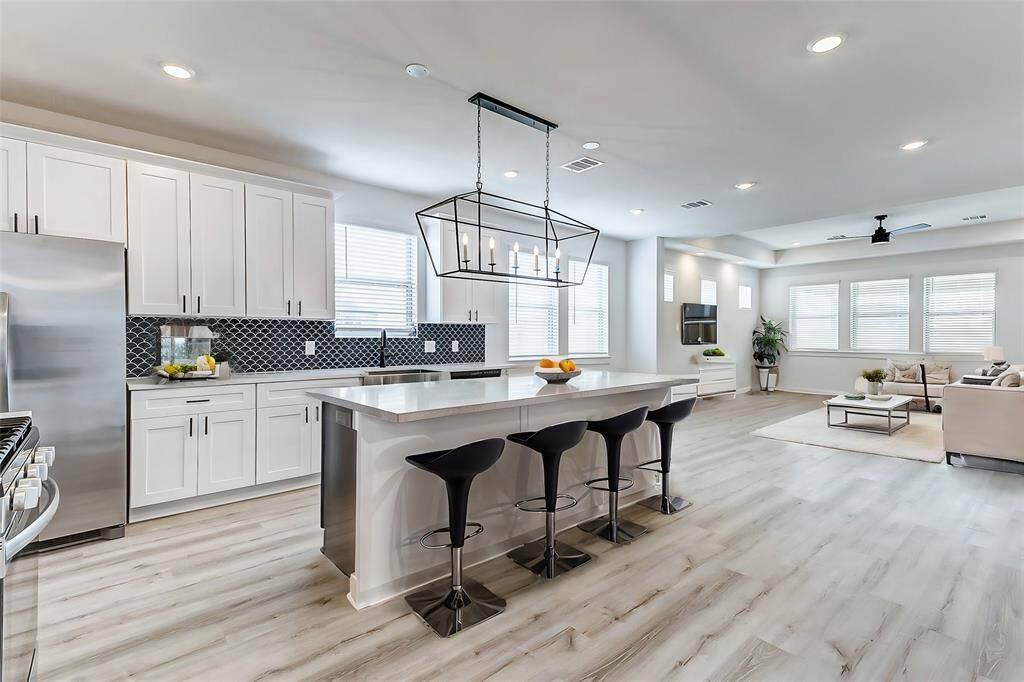 A chef’s dream! This gourmet kitchen boasts an oversized island, stainless steel appliances, pristine white cabinetry, and a stylish backsplash. The perfect place to whip up delicious meals while staying connected to the family. **This is a picture of a Rylan Floor Plan from another Saratoga Homes.**