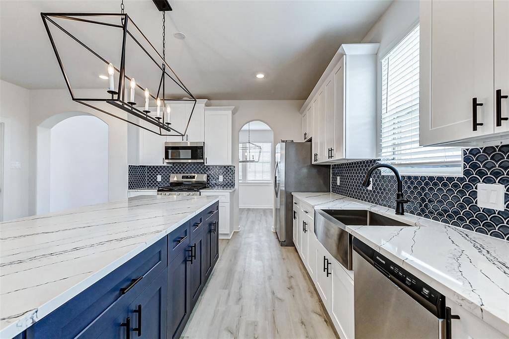 A chef’s dream! This gourmet kitchen boasts an oversized island, stainless steel appliances, pristine white cabinetry, and a stylish backsplash. The perfect place to whip up delicious meals while staying connected to the family. **This is a picture of a Rylan Floor Plan from another Saratoga Homes.**