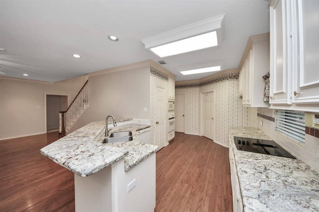 The stunning granite countertops beautifully complement the rich wood floors, adding a touch of elegance to the space.
