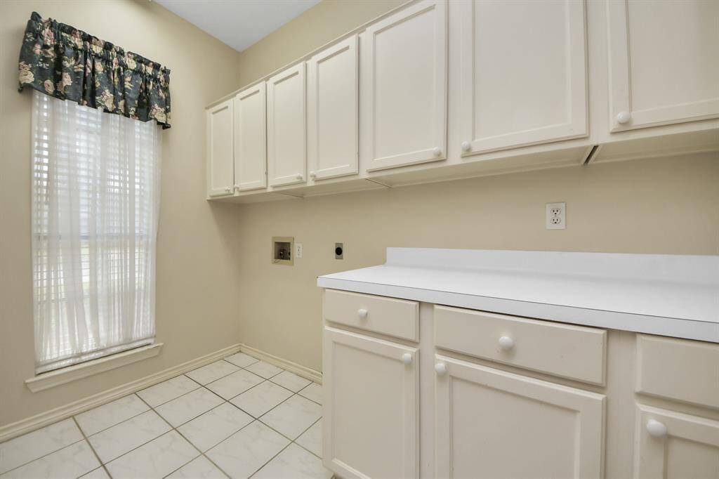The ample laundry room features countertop space for folding and a window that fills the room with natural light, making laundry a more cheerful experience.