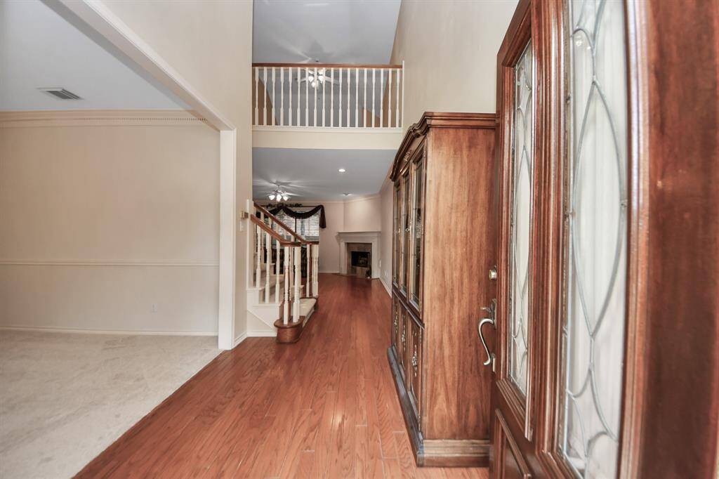 Step beyond the front door into a formal entryway featuring rich hardwood floors and soaring ceilings that create a grand first impression.