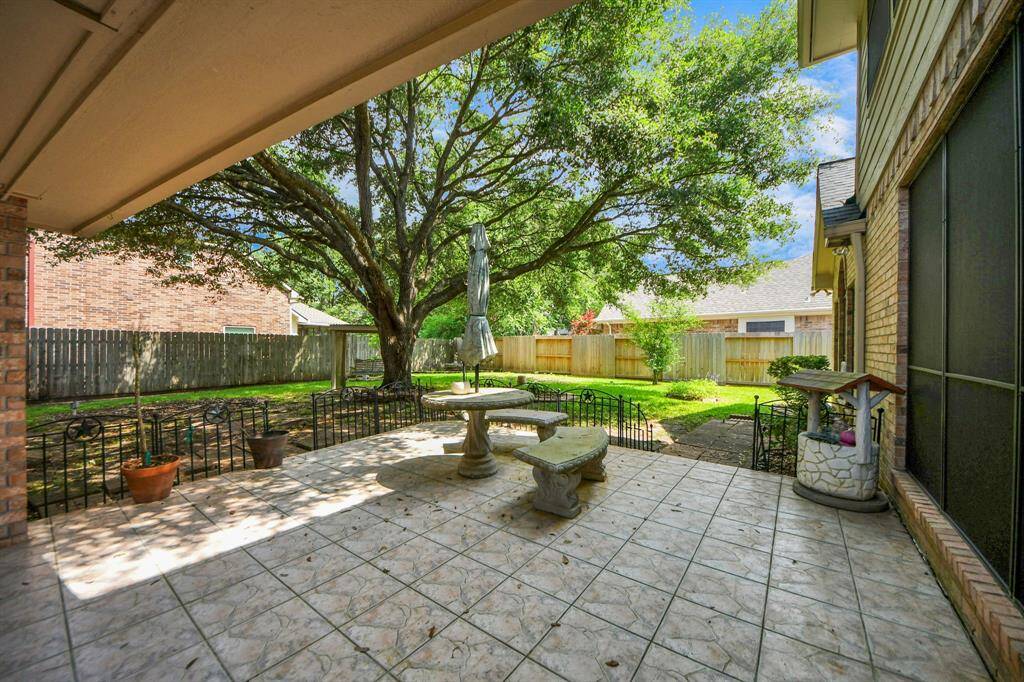 A large tiled back patio, complete with a covered walkway to the garage, offers a perfect space for outdoor relaxation and convenience.