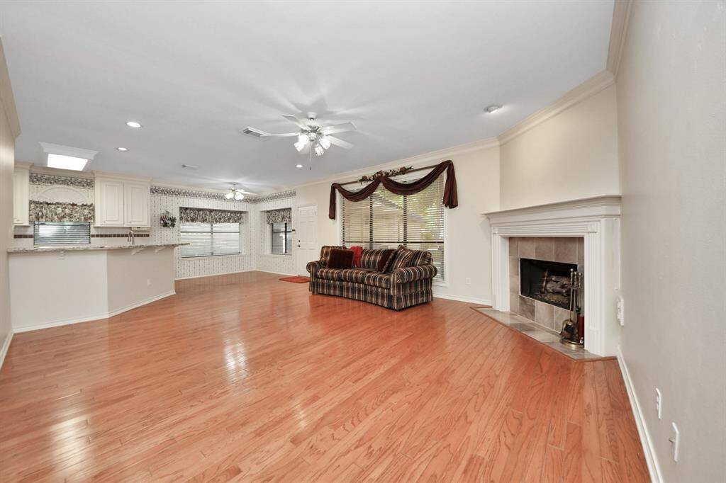 Beyond the entry, you are welcomed into the heart of the home—an inviting den anchored by a striking fireplace and framed by windows that offer serene views of the backyard.