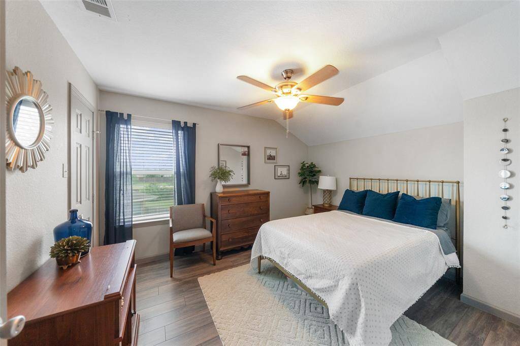A peek into one of the secondary bedrooms complete with ceiling fan and large window.
