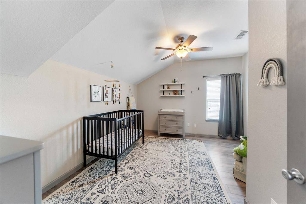 A peek into one of the secondary bedrooms complete with ceiling fan and large window.