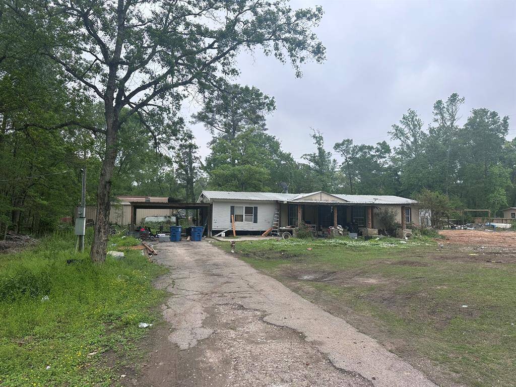 A fixer-upper opportunity on a spacious lot surrounded by trees. The property features a single-story home with a long driveway and potential for renovation or redevelopment in a serene setting.