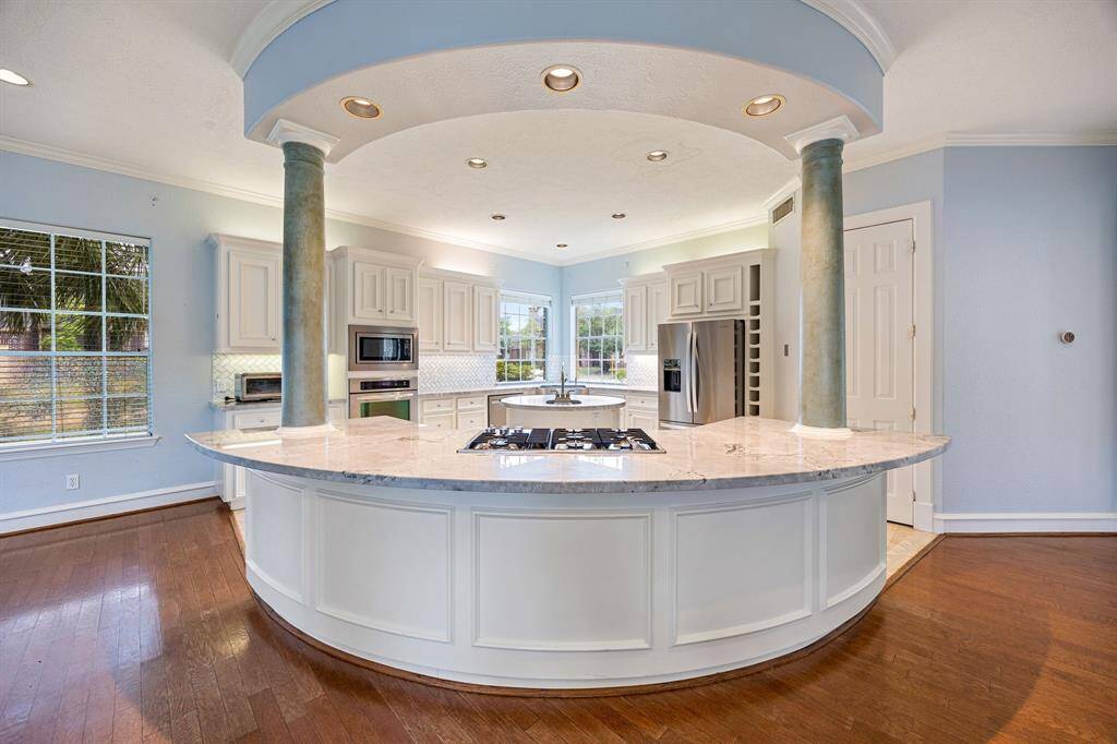 Remodeled kitchen offers a round island, farmhouse sink, gas cooktop, dual sinks, and stainless steel kitchen appliances.