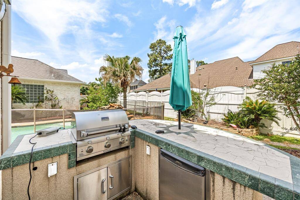 Outdoor kitchen with built-in grill, refrigerator and accent lighting.