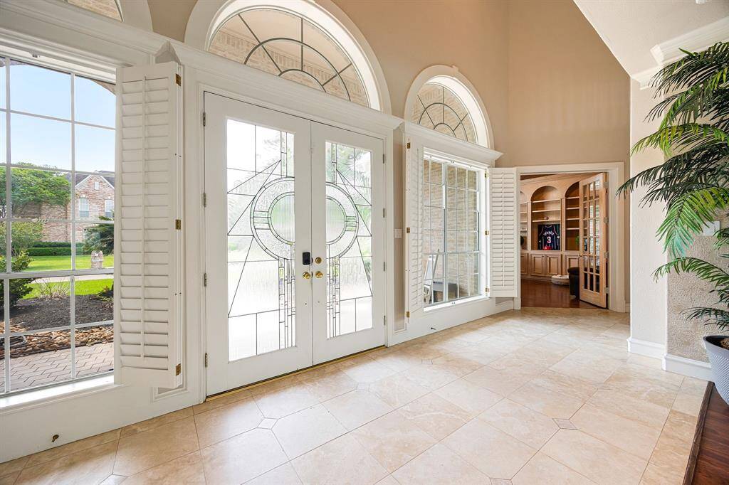This grand foyer sets the tone with soaring ceilings, Travertine flooring, custom windows, and timeless charm