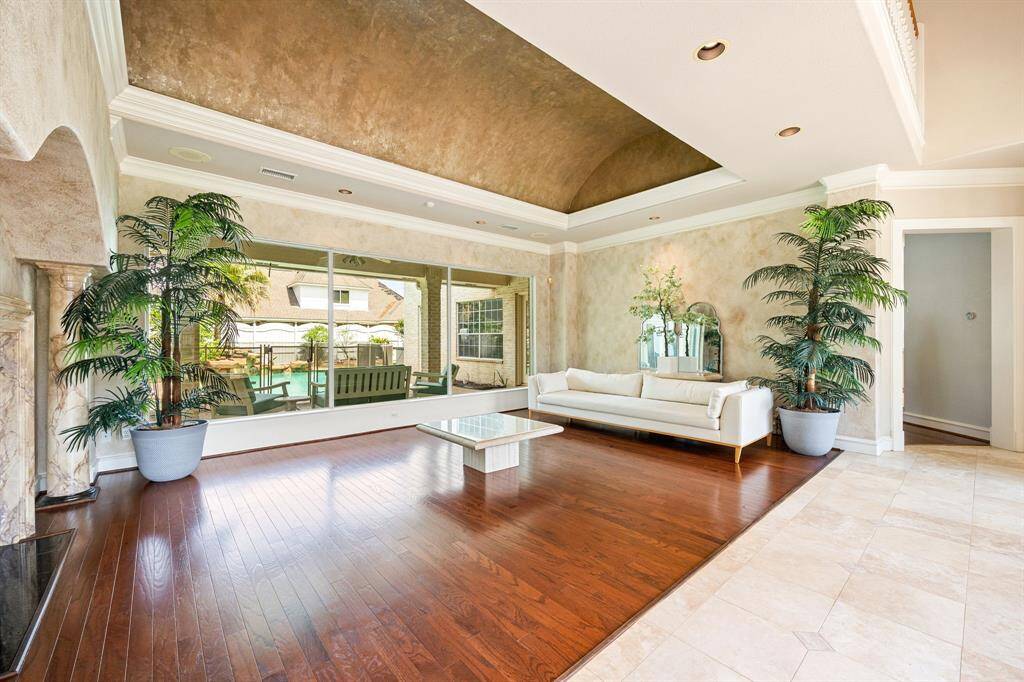Elegant formal living area with rich hardwood floors, soaring barrel ceilings, and expansive windows offering serene views of the backyard oasis.