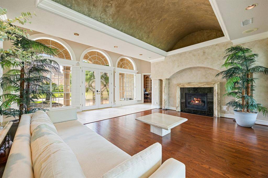Elegant arched windows with plantation shutters, & a cozy gas log fireplace framed in marble.