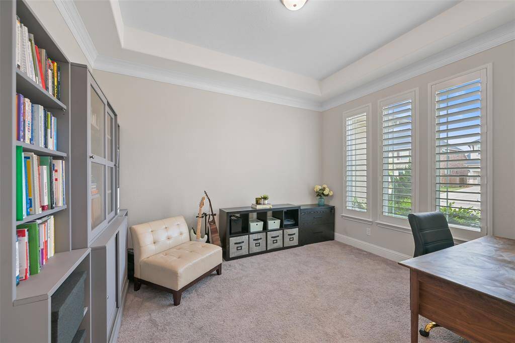 This flexible room, currently used as the study, offers endless possibilities—it could serve as a formal living room, study, or playroom to suit your needs. French doors open to reveal a spacious and inviting area, featuring a tray ceiling that adds architectural interest. The room is illuminated by a ceiling light, and the sellers have enhanced the space with elegant plantation shutters for added privacy and style.