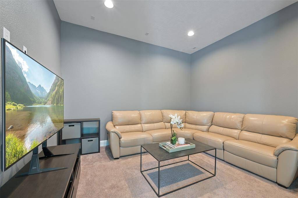 Double doors open from the game room to this sizable media room, designed for ultimate entertainment. The room features low-profile carpet for comfort and is pre-wired for speaker installation, making it perfect for a custom sound system. Recessed can lights provide the ideal lighting, creating a cozy and immersive atmosphere for movie nights or media viewing.